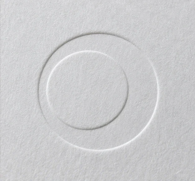 Detalhe ilustrativo de marca geométrica em relevo seco sobre papel branco